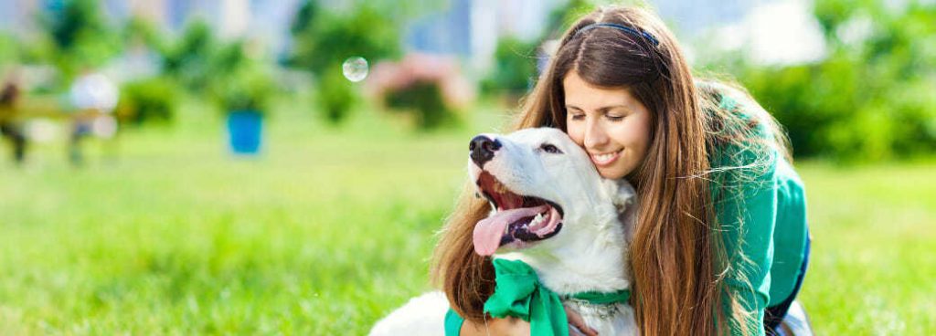 woman hugs white dog on all american pet photo day in a park